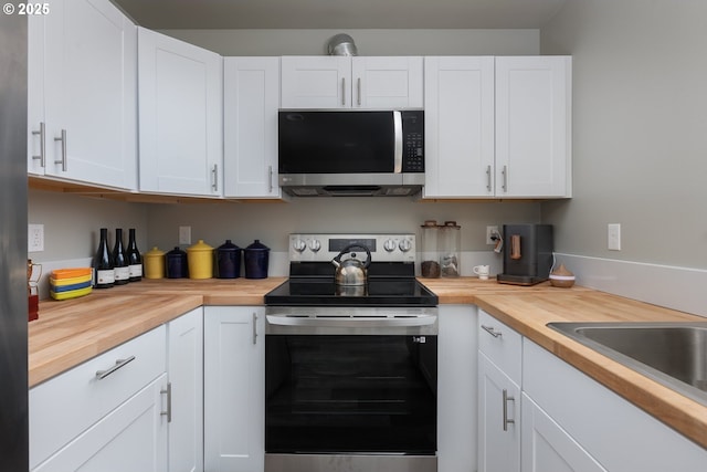 kitchen featuring butcher block countertops, stainless steel appliances, sink, and white cabinets