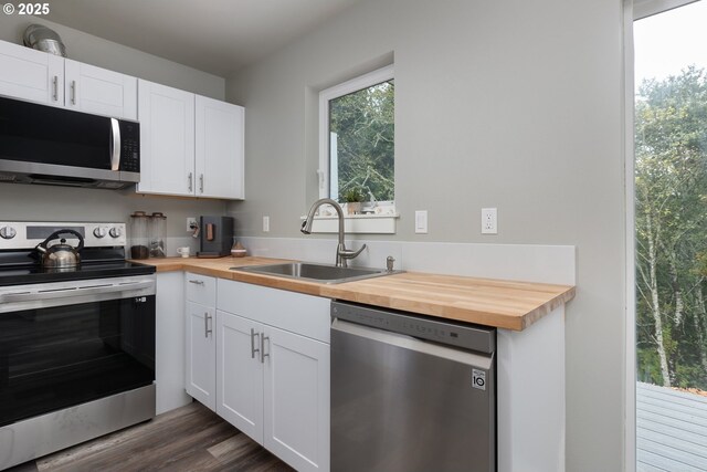 kitchen with white cabinets, appliances with stainless steel finishes, sink, and wooden counters