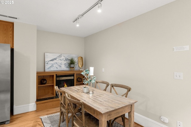 4113 SE Rural St, Portland, OR 97202 - dining area with light wood-style flooring, rail lighting, and a glass covered fireplace
