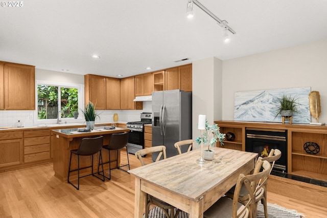 4113 SE Rural St, Portland, OR 97202 - kitchen with stainless steel appliances, a kitchen island, light wood-style floors, a kitchen breakfast bar, and recessed lighting