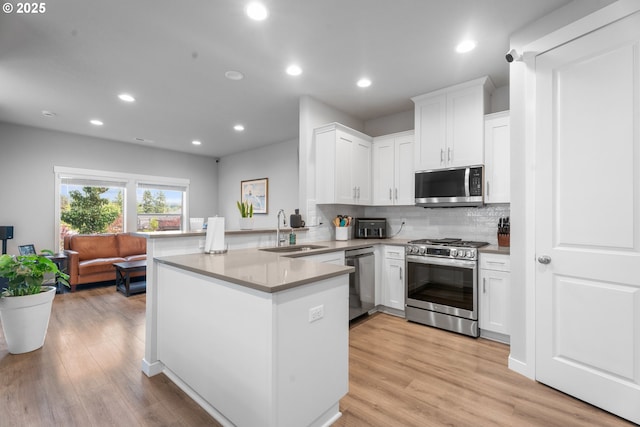 11465 SE Pleasant Valley Pkwy, Happy Valley, OR 97086 - kitchen with appliances with stainless steel finishes, a sink, a peninsula, white cabinetry, and tasteful backsplash