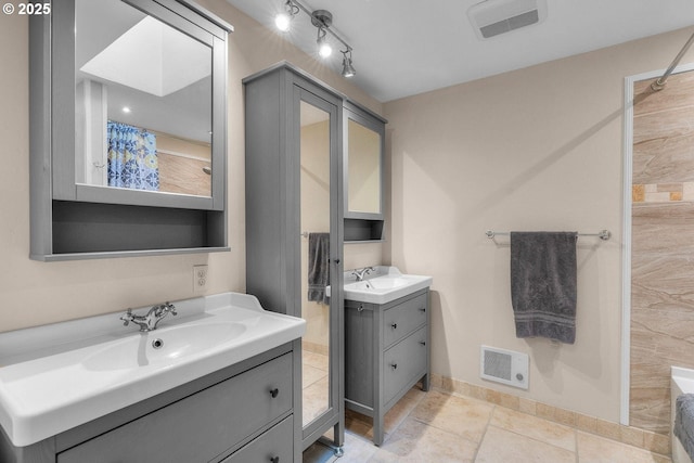 full bath featuring two vanities, baseboards, and tile patterned flooring