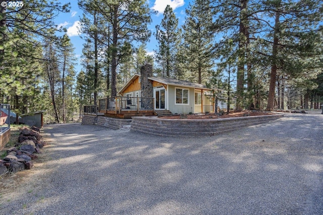 view of front of property featuring a chimney, a wooden deck, and driveway