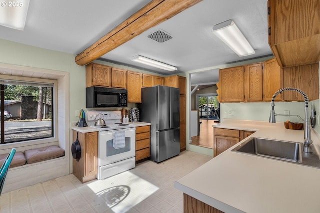 kitchen with black microwave, white range with electric stovetop, freestanding refrigerator, a sink, and light countertops