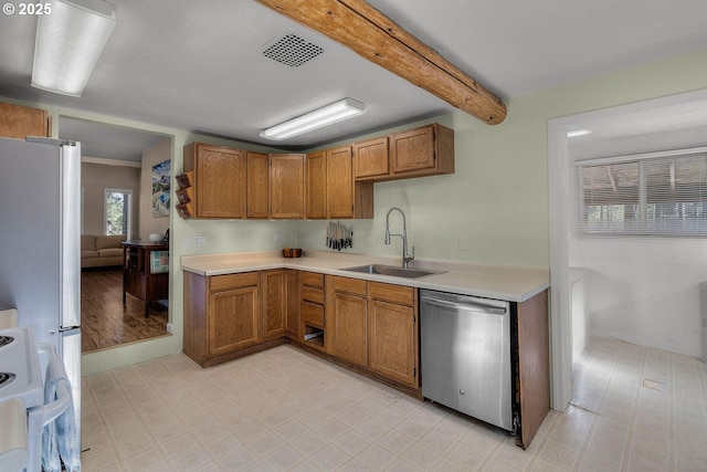 kitchen with stainless steel appliances, a sink, light floors, light countertops, and beam ceiling