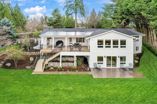 rear view of property with board and batten siding, a patio area, a yard, and stairway