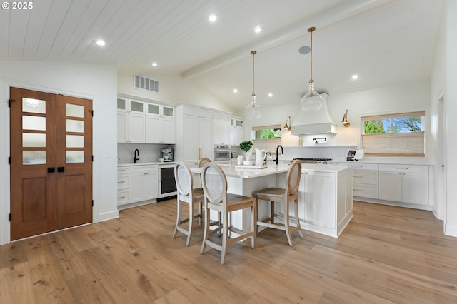 kitchen featuring a center island with sink, a sink, a kitchen breakfast bar, white cabinets, and recessed lighting