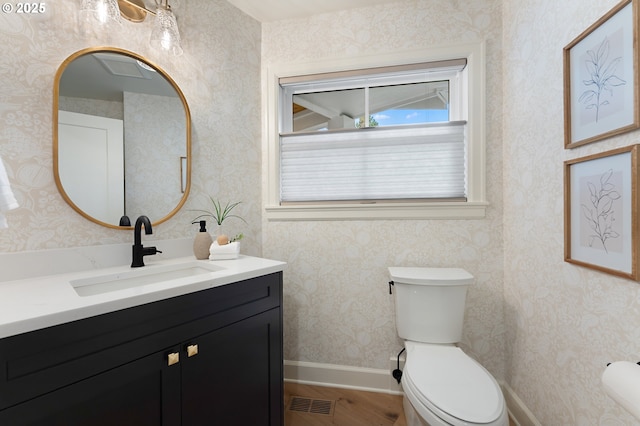 half bathroom featuring toilet, wood finished floors, and vanity