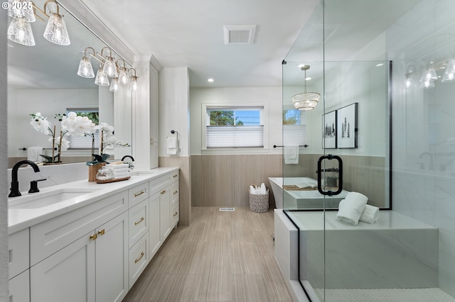 full bath with wainscoting, a shower stall, double vanity, and a chandelier