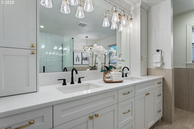 full bathroom with a shower stall, a wainscoted wall, and double vanity