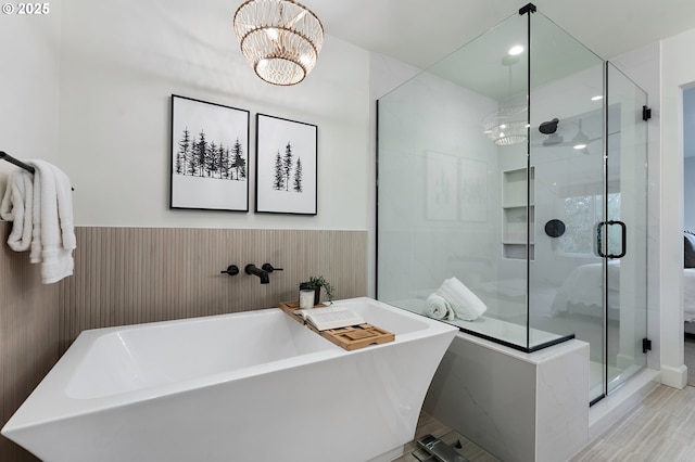 full bath featuring a shower stall, a chandelier, and a freestanding bath