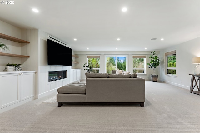 living area featuring recessed lighting, light colored carpet, a glass covered fireplace, and baseboards