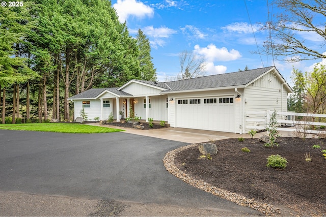 ranch-style home featuring board and batten siding, a garage, driveway, fence, and covered porch