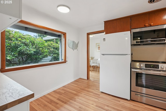 10544 SE Home Ave, Milwaukie, OR 97222 - kitchen featuring stainless steel appliances, light wood-type flooring, brown cabinets, and light countertops