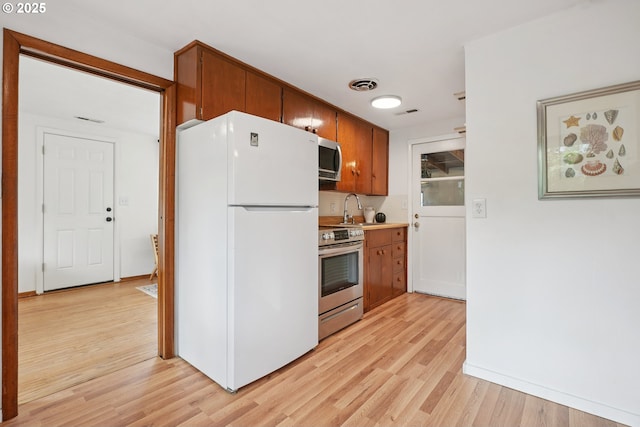 10544 SE Home Ave, Milwaukie, OR 97222 - kitchen featuring stainless steel appliances, light wood-style flooring, brown cabinetry, and light countertops