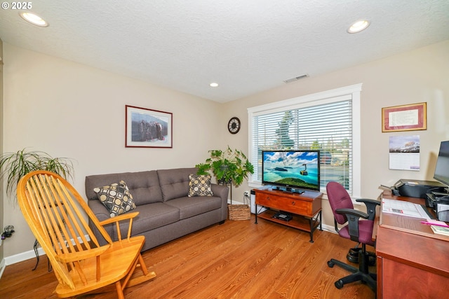 home office featuring light hardwood / wood-style flooring and a textured ceiling