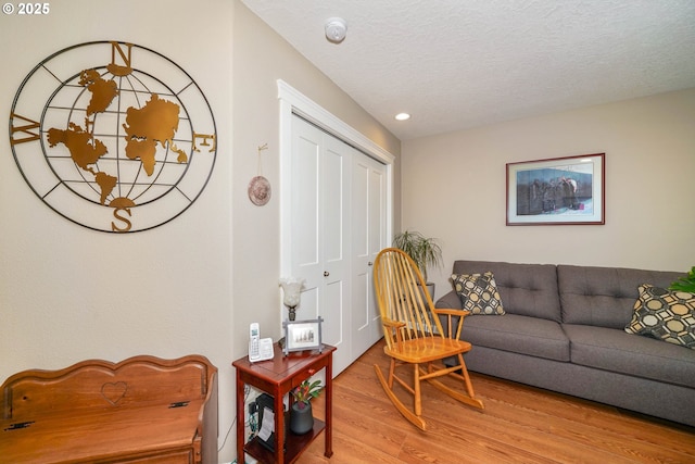 living room with a textured ceiling and light wood-type flooring