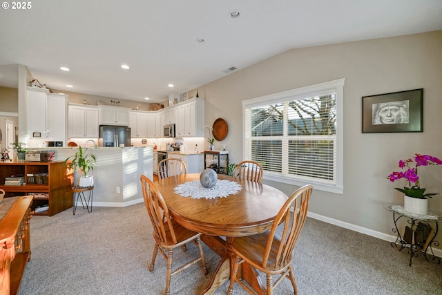 dining room with vaulted ceiling and light colored carpet