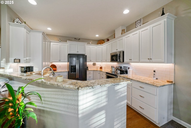 kitchen with white cabinetry, appliances with stainless steel finishes, light stone counters, and decorative backsplash