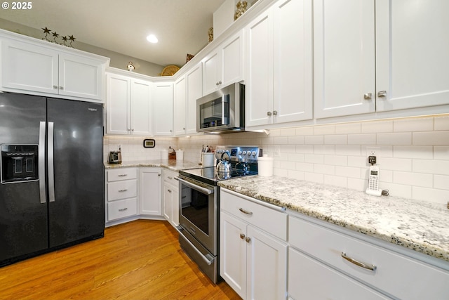 kitchen featuring white cabinetry, light stone counters, light hardwood / wood-style flooring, appliances with stainless steel finishes, and decorative backsplash