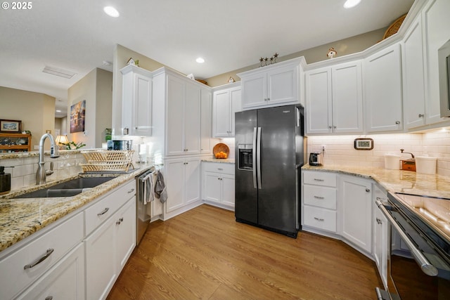 kitchen with appliances with stainless steel finishes, sink, white cabinets, and light wood-type flooring