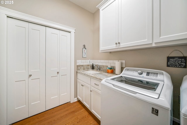 laundry room with sink, light hardwood / wood-style floors, cabinets, and washing machine and dryer