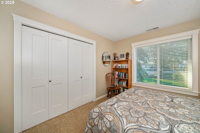 carpeted bedroom with a closet and a textured ceiling