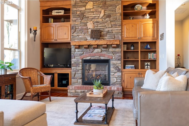 living area featuring wood finished floors, built in shelves, and a fireplace