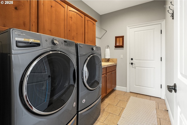 clothes washing area featuring baseboards, cabinet space, light tile patterned floors, and washing machine and clothes dryer