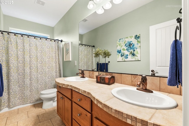 bathroom featuring visible vents, a sink, double vanity, and toilet