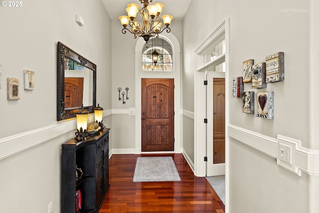 foyer with a towering ceiling, wood finished floors, and a chandelier