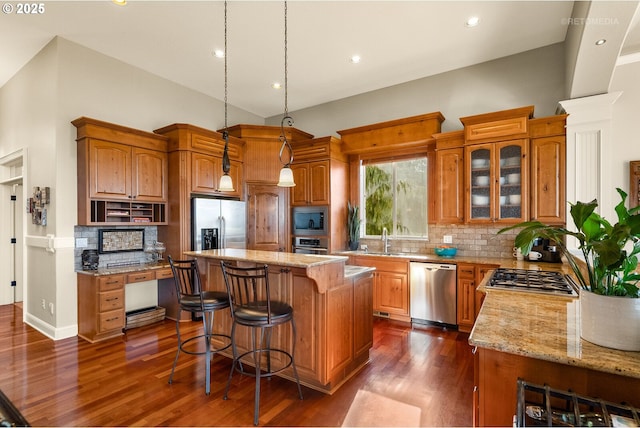 kitchen with a kitchen breakfast bar, a kitchen island, dark wood-style flooring, light stone countertops, and stainless steel appliances