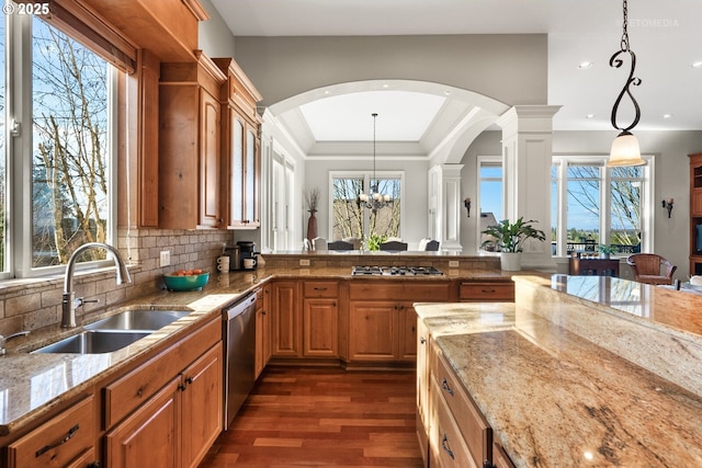 kitchen featuring a sink, arched walkways, dark wood finished floors, stainless steel appliances, and a wealth of natural light
