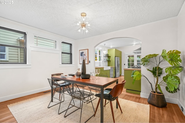 2942 NE 34th Ave, Portland, OR 97212 - dining area with arched walkways, light wood finished floors, a textured ceiling, and baseboards