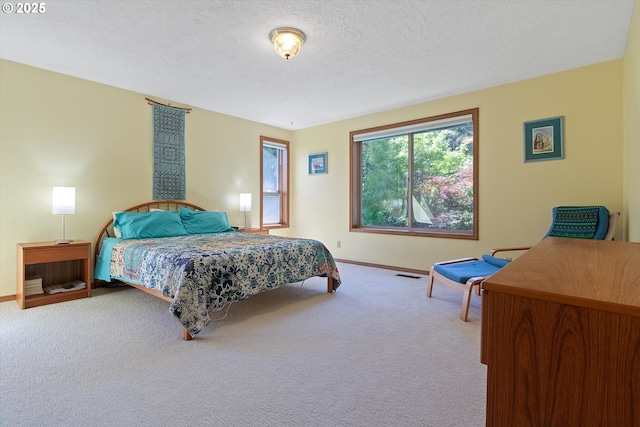 carpeted bedroom featuring a textured ceiling, visible vents, and baseboards