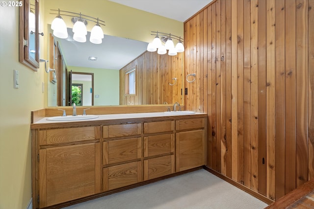 bathroom with double vanity, wood walls, and a sink