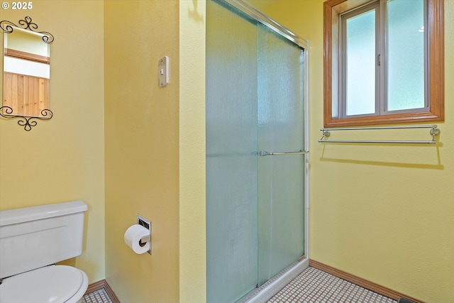 bathroom with baseboards, a shower with shower door, and toilet