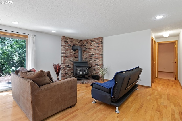 living area featuring a textured ceiling, recessed lighting, baseboards, light wood-type flooring, and a wood stove