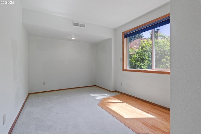 carpeted spare room featuring visible vents and baseboards