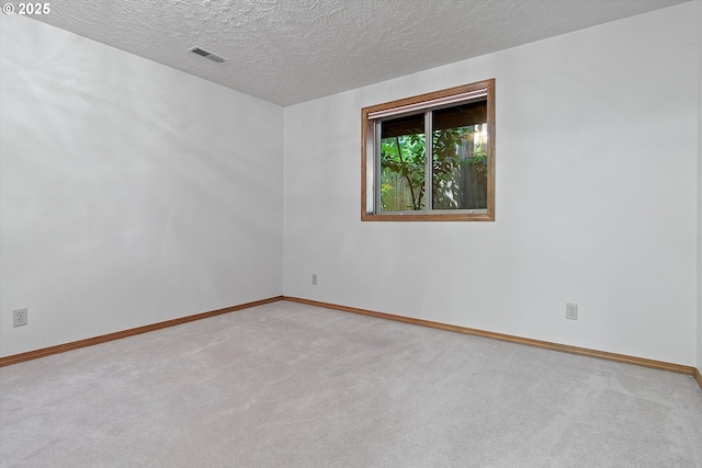 empty room featuring a textured ceiling, carpet flooring, visible vents, and baseboards