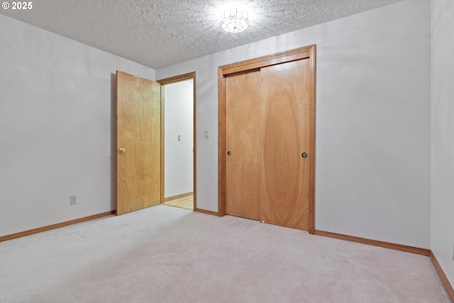 unfurnished bedroom featuring a closet, carpet flooring, a textured ceiling, and baseboards