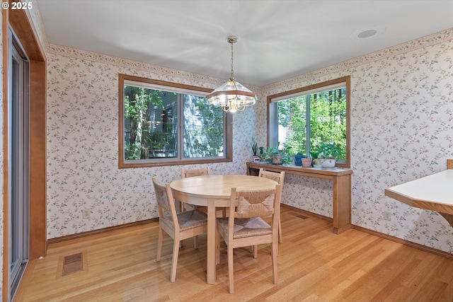 dining room featuring baseboards, light wood-style floors, visible vents, and wallpapered walls