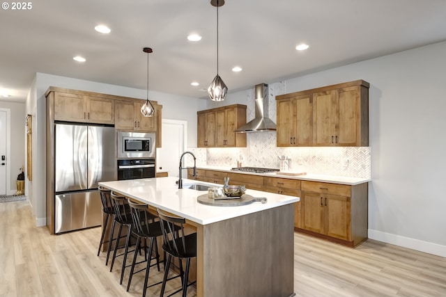 kitchen featuring appliances with stainless steel finishes, pendant lighting, sink, decorative backsplash, and wall chimney range hood