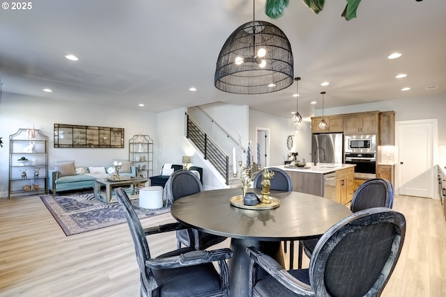 dining room with sink, a notable chandelier, and light hardwood / wood-style flooring