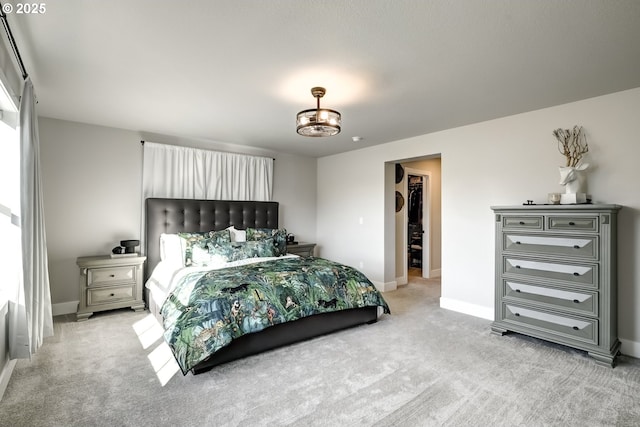 bedroom with a spacious closet and light colored carpet