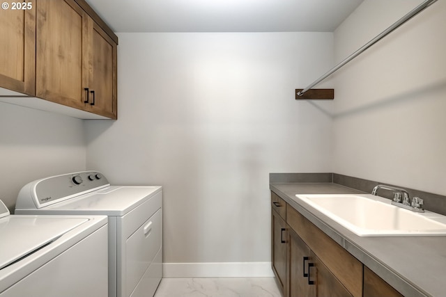 clothes washing area with cabinets, sink, and washer and clothes dryer