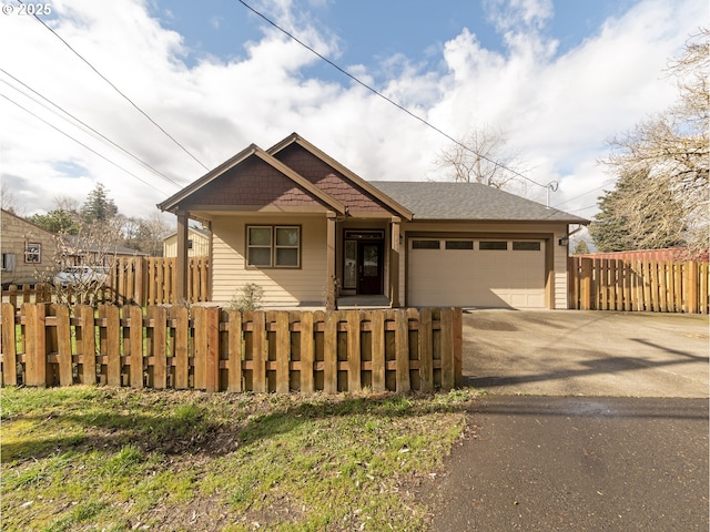 view of front of house featuring an attached garage, driveway, and a fenced front yard