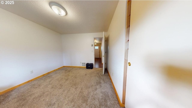 spare room featuring baseboards, light carpet, a textured ceiling, and visible vents