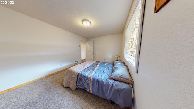 carpeted bedroom with a textured wall, baseboards, and a textured ceiling