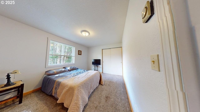 carpeted bedroom with a closet, a textured ceiling, and baseboards